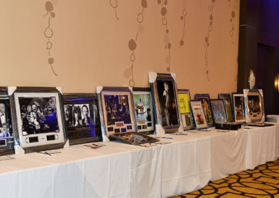 A row of framed photographs and memorabilia displayed on a table at an event venue.