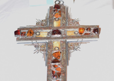 Decorative cross displayed on a table at an event with a 'silent auction' sign, featuring intricate metal and amber embellishments.
