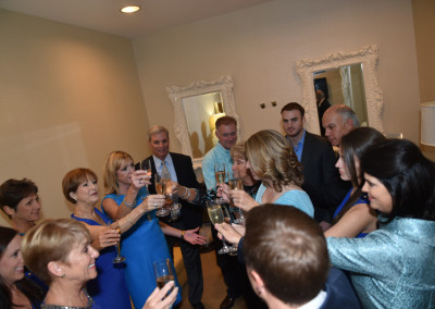 A group of adults raising glasses in a celebratory toast at an indoor gathering.