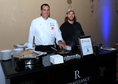 Two chefs cooking at a catering station with a "tallulah" sign at a renaissance hotel event.