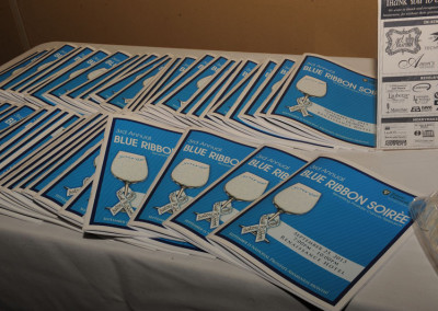 Programs for the 3rd annual blue ribbon soiree neatly arranged on a table.