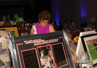 Woman examining a framed sports memorabilia item at a charity auction event.