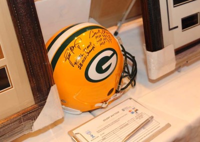 A signed green bay packers helmet on display next to a silent auction bid sheet on a table.