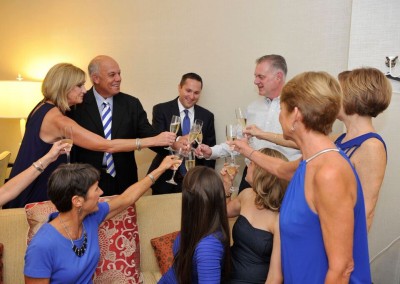 Group of seven adults toasting with champagne in a cozy room.