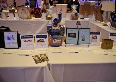 A silent auction table displaying various prize items including gift baskets and certificates.