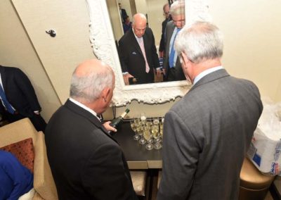 A group of men looking at a mirror in a room.