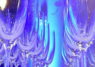 A display of sparkling wine glasses illuminated by blue lighting.