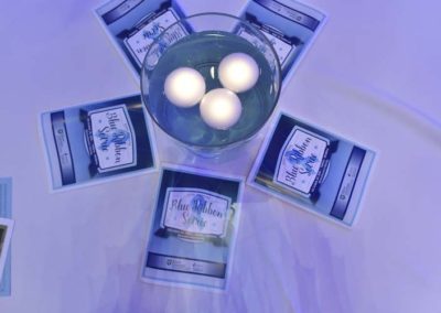 Overhead view of a table centerpiece featuring a glass bowl with three white spheres surrounded by cards titled "blue ribbon service.