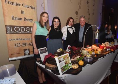 Four people standing behind a catering table at a formal event in baton rouge, smiling for a photo.