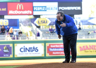 A man in a blue jacket standing on top of a baseball field.