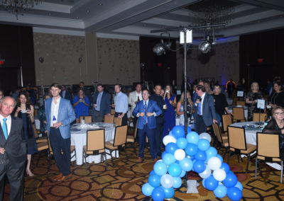 Business professionals attending a conference in a banquet hall with blue balloon decorations.