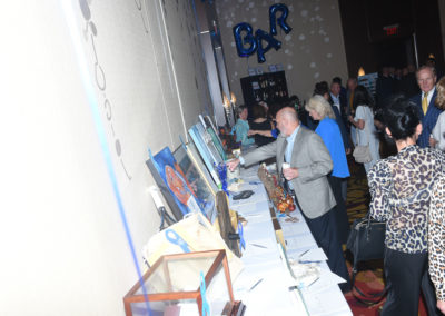 Guests at a gala event browsing items on a silent auction table.