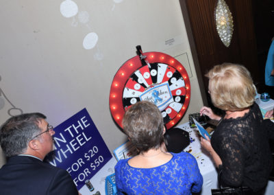 People at a charity event spin a prize wheel to win giveaways.