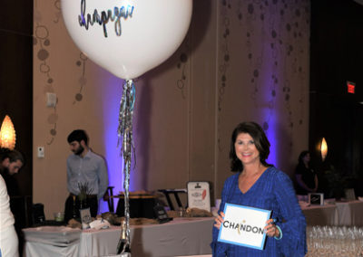 A woman holding a balloon in front of a table full of wine glasses.