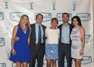 Five adults smiling for a photo at an event with a "blue ribbon schools" banner in the background.