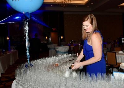 A woman pouring wine at a table with balloons.