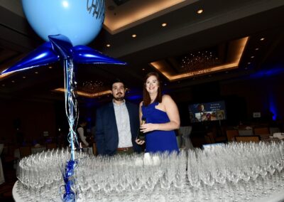 A man and woman standing next to a table full of wine glasses.