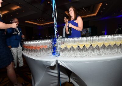 A group of people standing near a table full of champagne glasses.