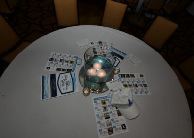 Round table covered with promotional materials and a glowing lamp centerpiece in a dimly lit room.