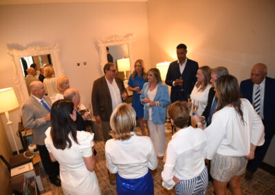 A group of people engaging in conversation at a social gathering in a room with elegant decor.