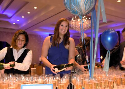 A woman in a blue dress stands beside a balloon and a table filled with champagne glasses at a chandon event.