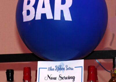 A large blue balloon with "bar" written on it is displayed above a selection of alcoholic beverages and promotional signs.