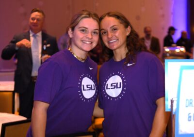 Two women wearing lsu t-shirts smiling at a conference event.